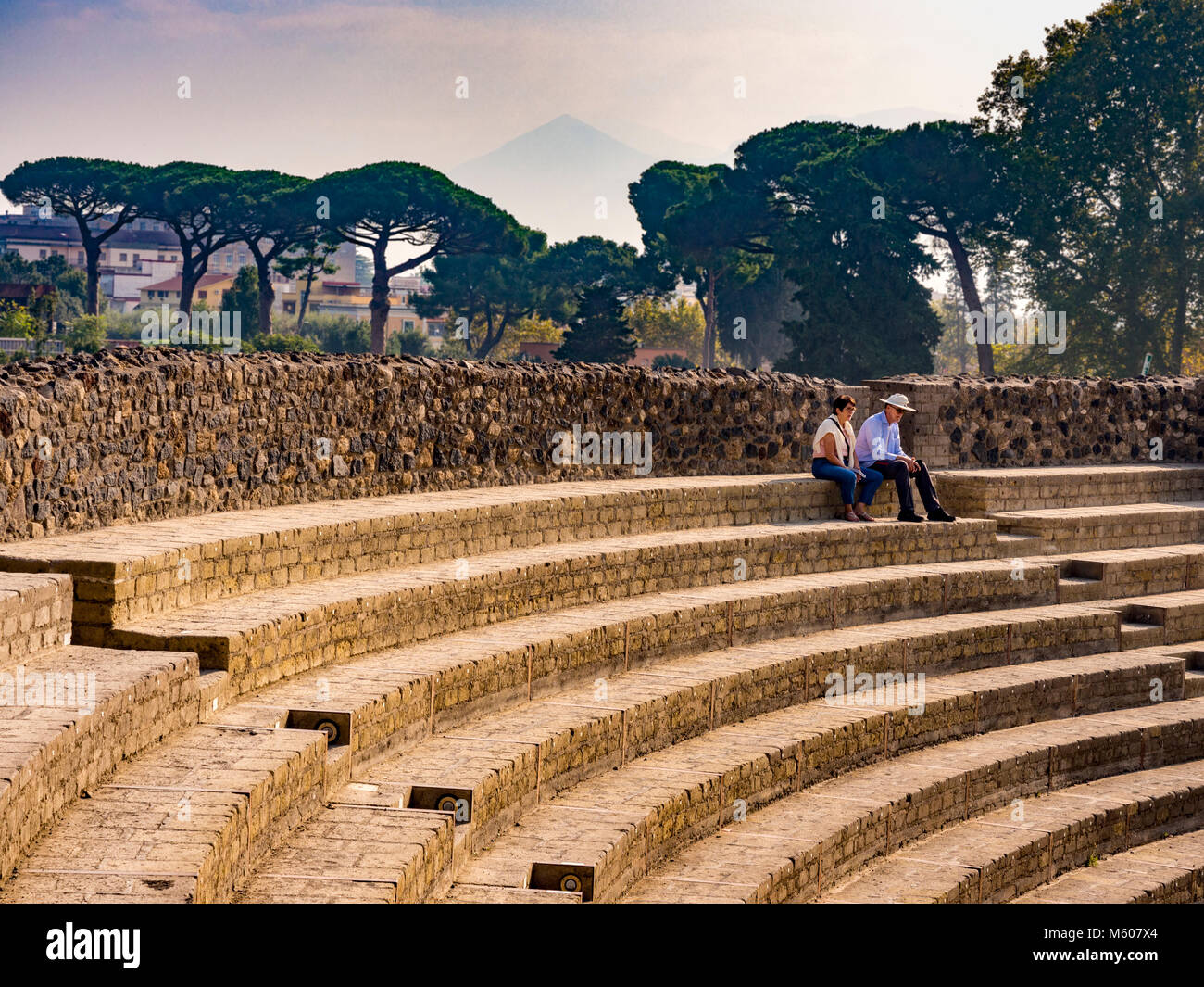 2 Personen sitzen auf Steintreppen im Großen Theater Cavae (Zuschauerbereich), den Ruinen von Pompeji, Italien. Stockfoto