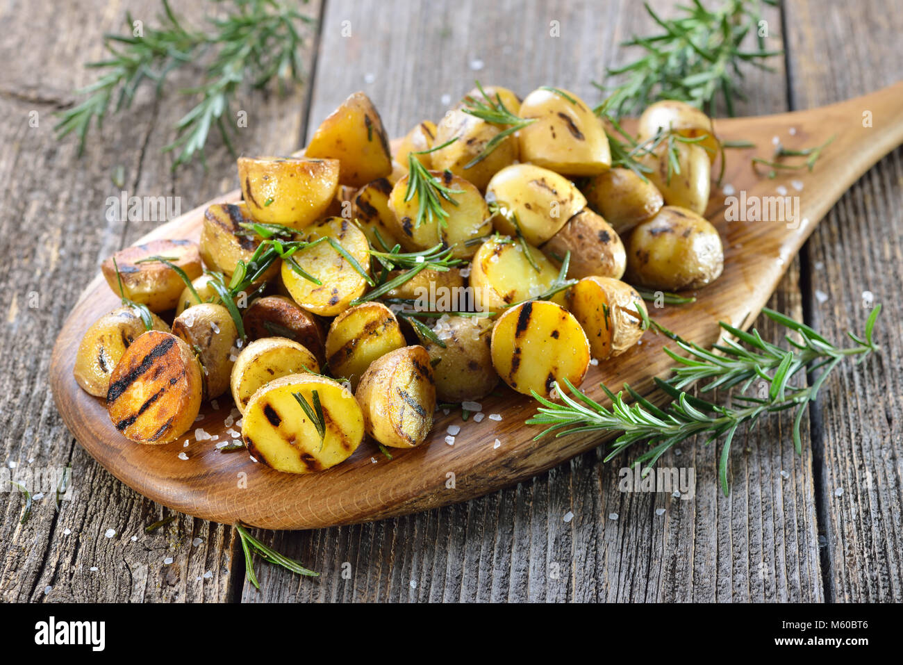 Vegane Küche: gegrilltes baby Kartoffeln mit Rosmarin auf einem Holzbrett serviert. Stockfoto