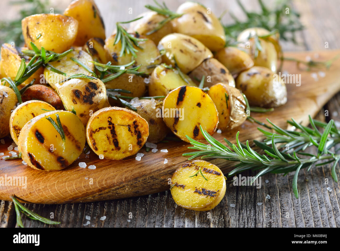 Vegane Küche: gegrilltes baby Kartoffeln mit Rosmarin auf einem Holzbrett serviert. Stockfoto