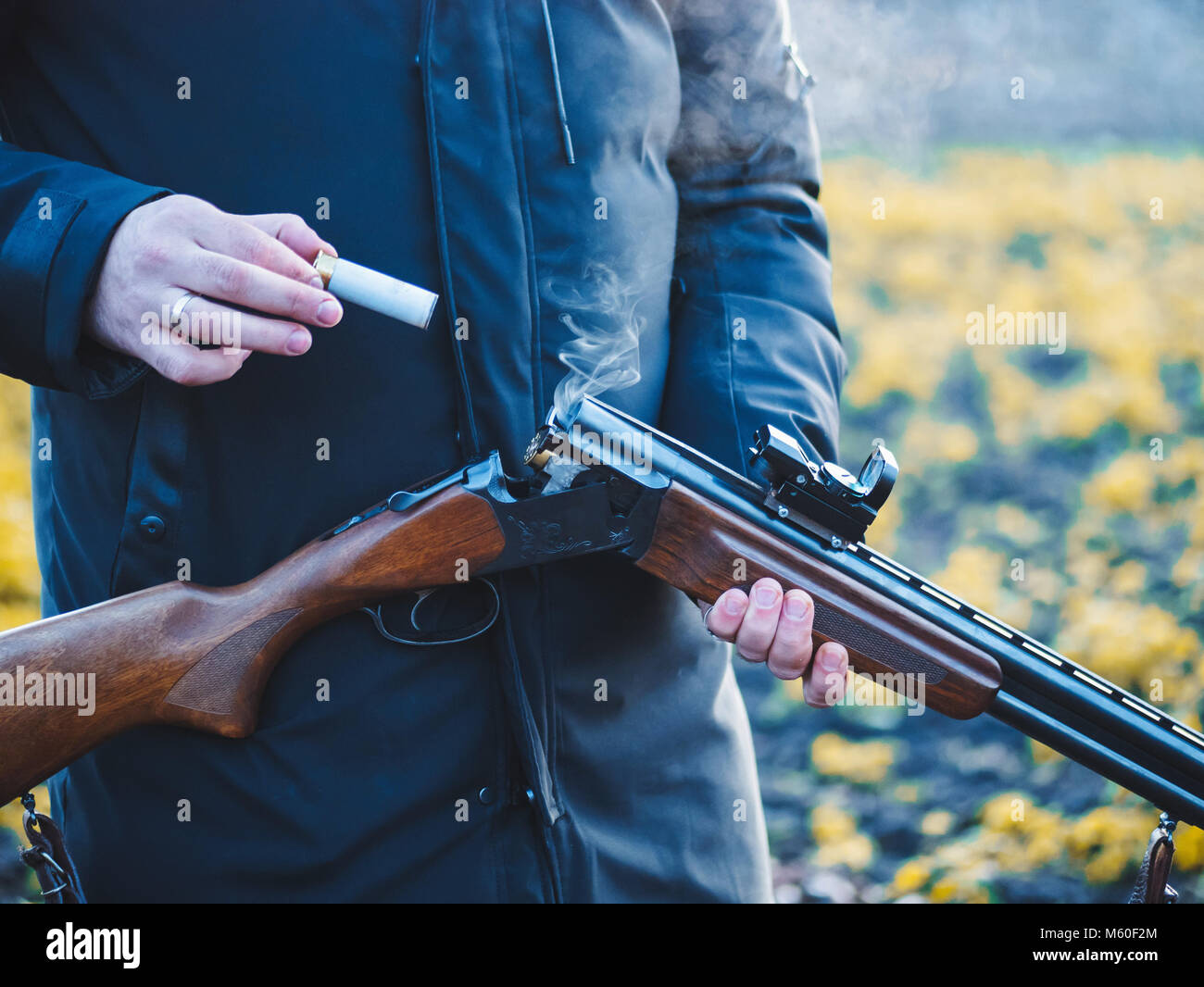 Sport schießen. Hunter nachladen Patrone in das Feld ein. Rauch aus den Stämmen von glattem Jagdwaffe nach dem Feuern. Stockfoto