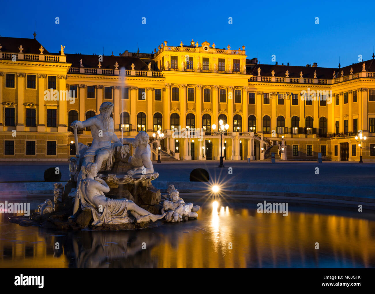 Schloss Schönbrunn und einer der Naiad Brunnen (Geister von Quellen und Flüssen) bei Nacht beleuchtet, Schönbrunn, Wien, Österreich. Stockfoto