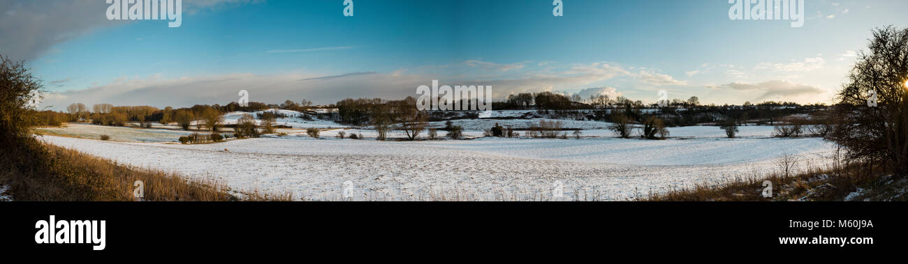 Fynn Tal, Suffolk, England. 27. Februar 2018. Panoramablick über Schnee beladene Felder auf einem späten Winter am Nachmittag. Viel von dem Schnee, der mit 'kam das Tier aus dem Osten 'kalten Wetter am Nachmittag Sonne geschmolzen. Die Sonne steht tief am Himmel auf der extremen Rechten Seite des Fotos. Dies schafft Lange weiche Schatten, die sich über die Felder von Bäumen, die von der Sonne beleuchtet werden. Die warmen Farben der Abend Himmel kann knapp über dem Horizont gesehen werden, niedrig in den Himmel. Dieses Panorama ist fast 180 Grad erstreckt sich eine Weite der Landschaft. Foto Stockfoto