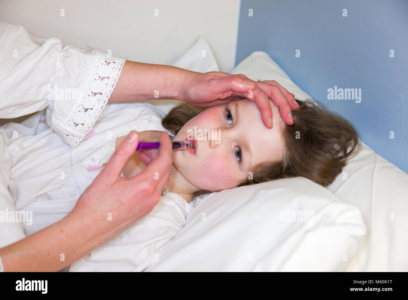 Mutter/Mom/mom geben einen Souvenierladen Medizin mit Paracetamol -  offenbar ein-krank/krank Kind/Kind/Mädchen im Bett mit Fieber oder  Temperatur. (95 Stockfotografie - Alamy