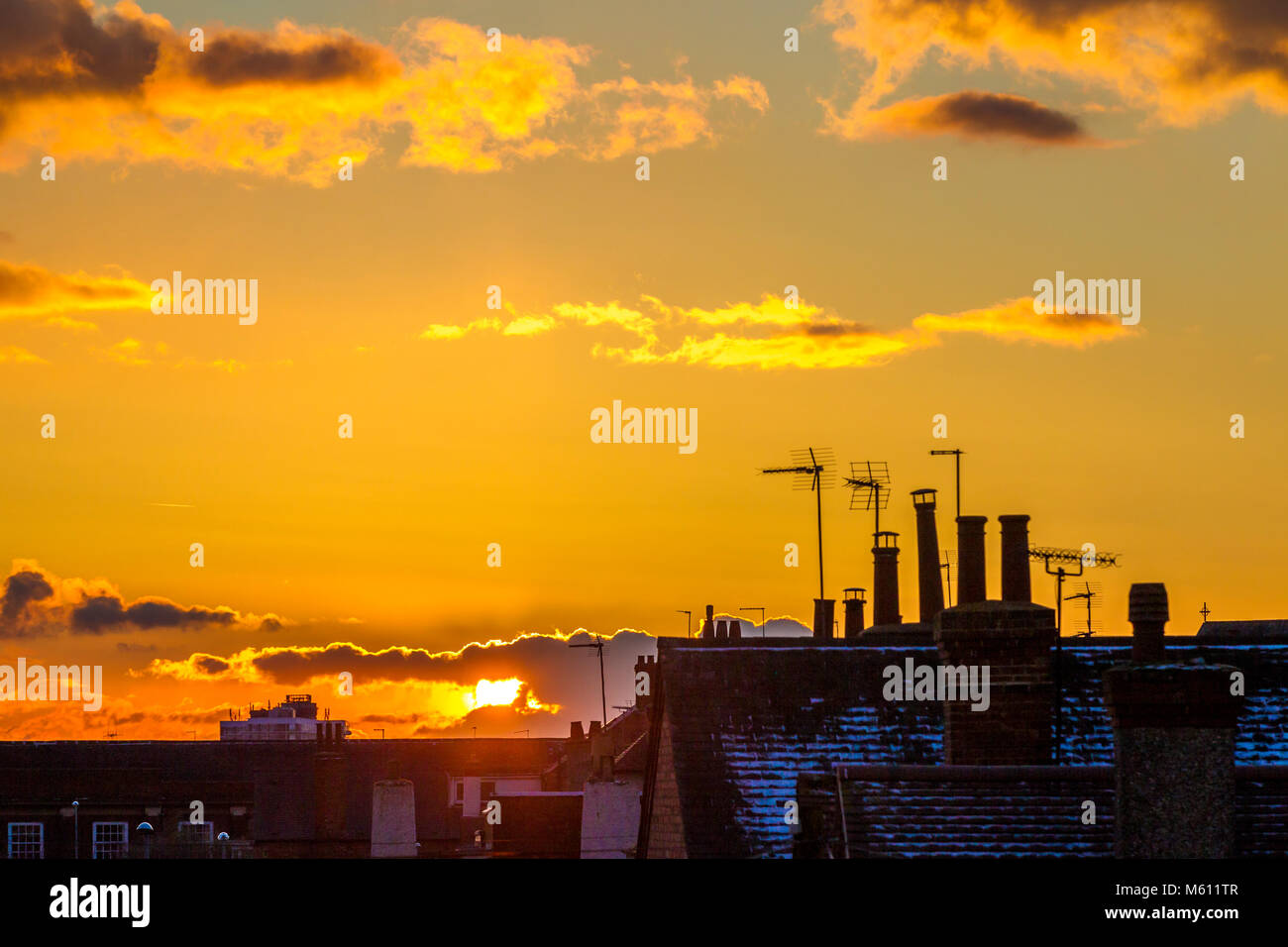 Northampton, Großbritannien 27. Februar 2018. Wetter. Bunte Ende an den Tag über die Dächer in einen goldenen Sonnenuntergang und ein helles Abstauben der Schnee auf den Dächern. Credit: Keith J Smith./Alamy leben Nachrichten Stockfoto