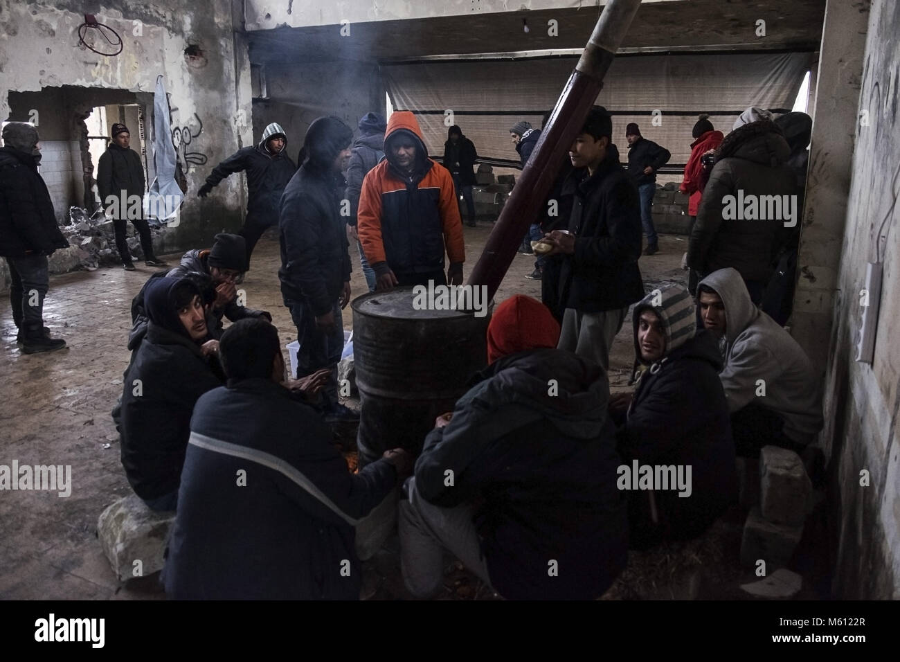 Sid, Vojvodina, Serbien. 9 Feb, 2018. In einer verlassenen Fabrik in der Nähe der serbisch-kroatischen Grenze Flüchtlinge und Migranten um einen Holzofen sammeln warm zu halten. Sid ist eine Stadt im Bezirk Srem der autonomen Provinz Vojvodina, Serbien. Die Stadt von Sid ist direkt neben der serbisch-kroatischen Grenze entfernt. Die balkanroute wurde offiziell vor über einem Jahr mit Kroatien und Ungarn Erhöhung der Sicherheit der Grenzen, die Migranten und Flüchtlinge in Serbien klemmt geführt hat geschlossen. Während die Grenzen um Serbien angezogen gibt es noch eine Stockfoto