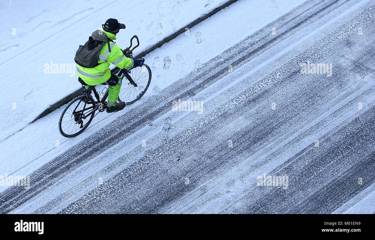 Ein Mann in Gut sichtbare Kleidung Zyklen entlang der Küste von Brighton heute morgen nach einer Nacht mit Frost und Schnee duschen. 27. Februar 2018 Stockfoto