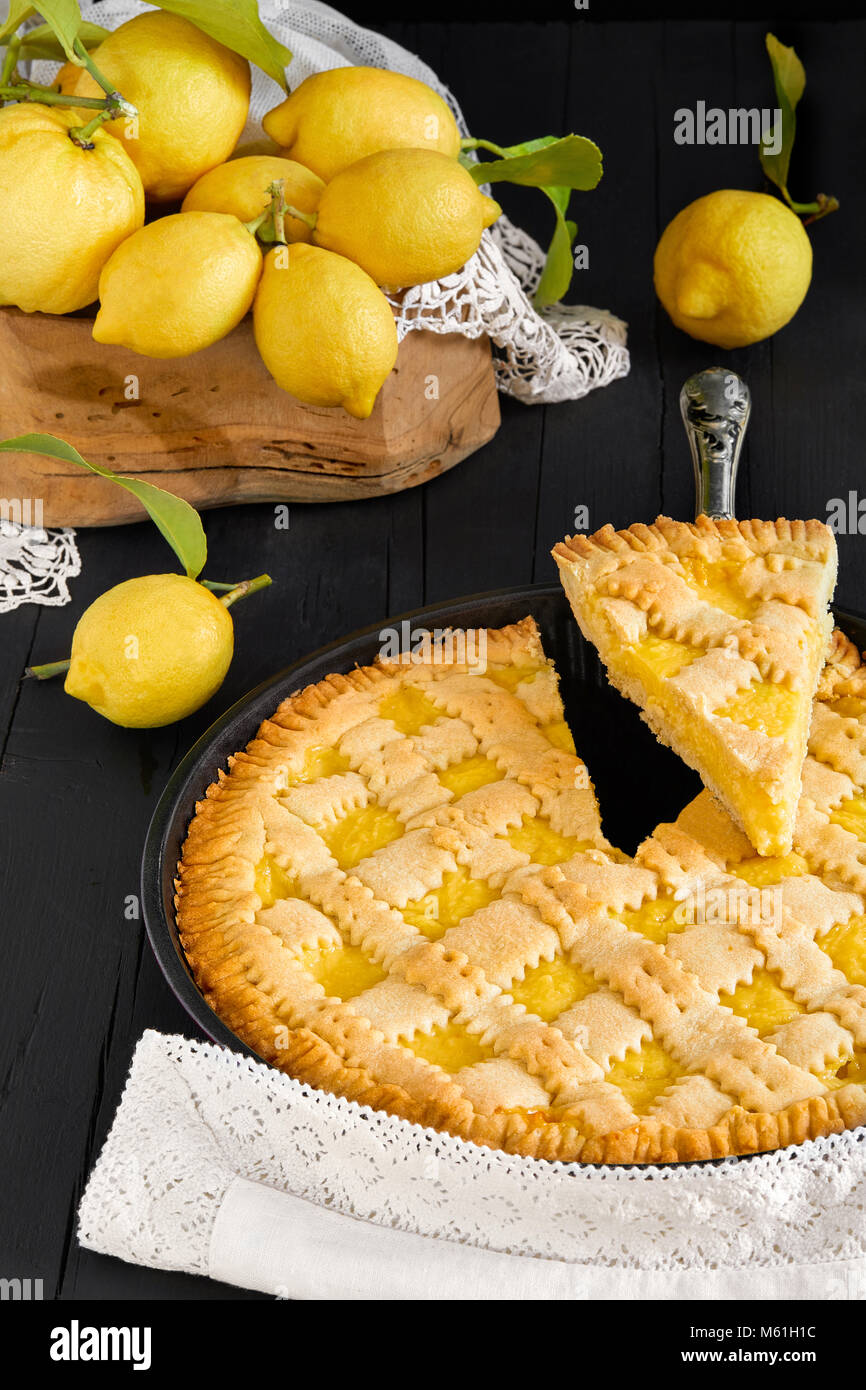 Close-up Lemon Pie mit einer Scheibe geschnitten und frischen Zitronen. Stockfoto