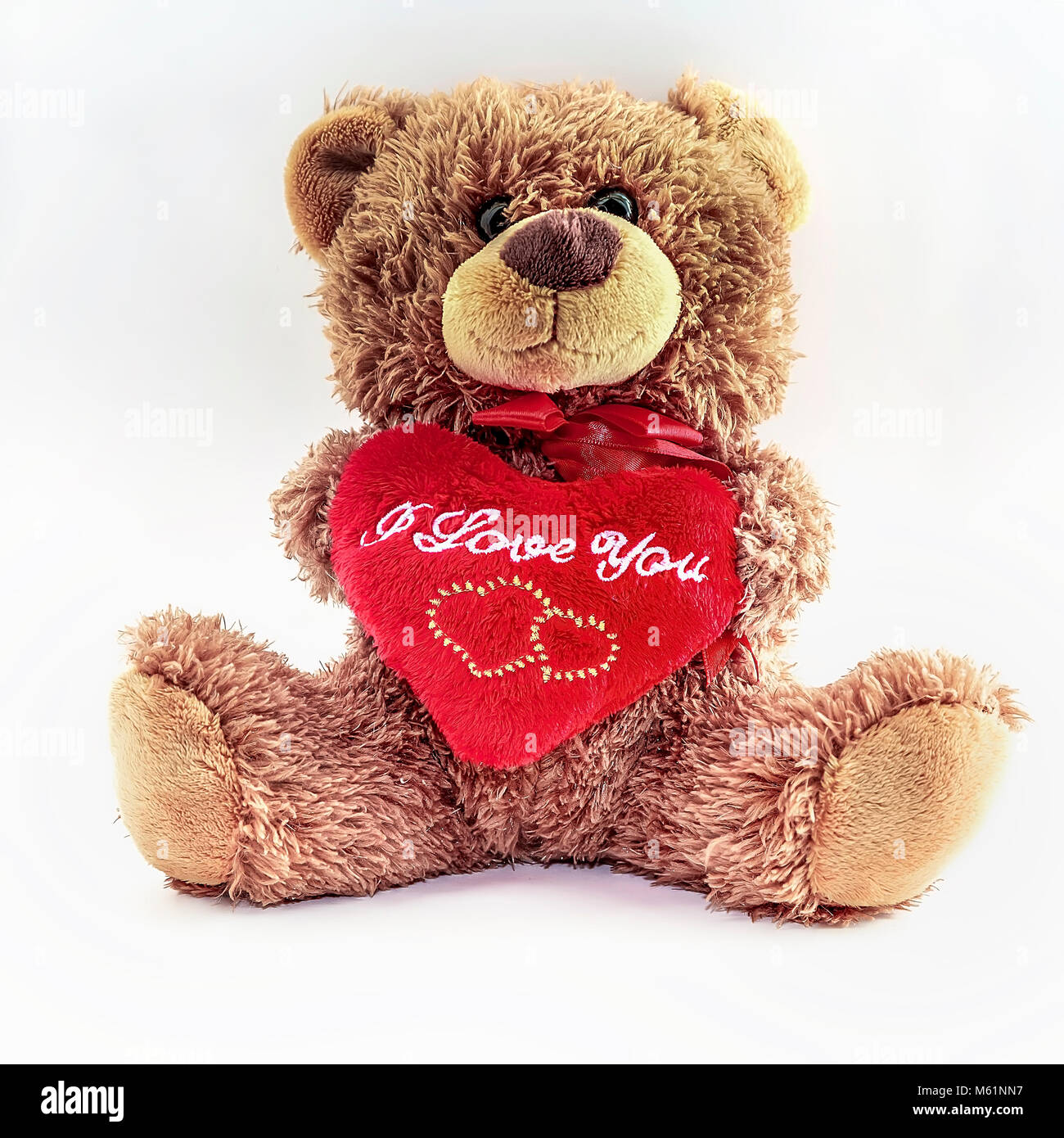 Plüschtier Teddy sitzend hält ein rotes Herz mit der Botschaft, die ich euch liebe. Isoliert. Stockfoto