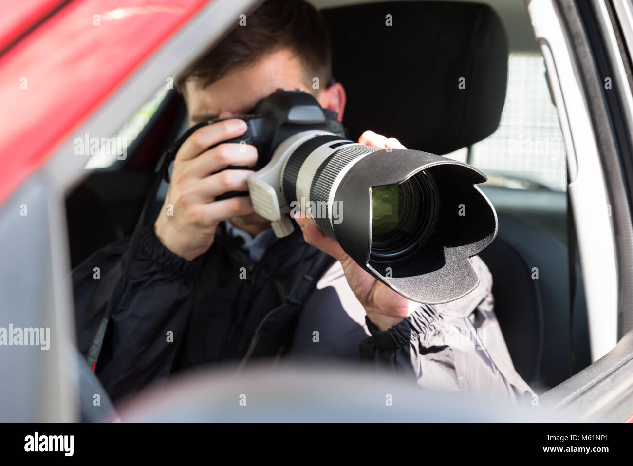 Seitenansicht eines Privatdetektiv Sitzen im Auto Fotografieren mit SLR-Kamera Stockfoto