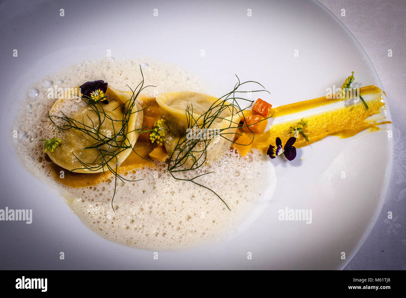 Gefüllte Nudeln in einer leichten Rahmsauce gehören zur Abendkarte des Restaurants Ernerle im Romantik Hotel Das Schiff, Hittisau, Vorarlberg, Österreich. Würfelkürbis, Fenchelgrün und essbare Blüten garnieren den Teller. Stockfoto