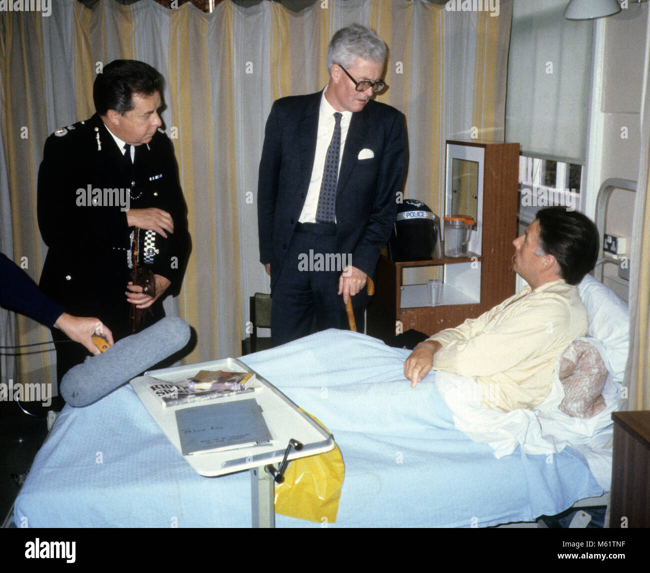 British Home Secretary Douglas Hurd, verletzten Polizisten im Krankenhaus nach der Tottenham Unruhen auf Broadwater Farm Estate in 1985. Auf der linken Seite ist stellvertretender Leiter des Metropolitan Peter Imbert, der später Baron Imbert. Stockfoto