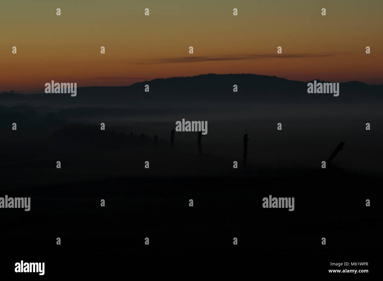 Nacht Foto mit eingezäunten Wiesen südlich von Sønderho mit Nebel und die Sonne den Horizont herab Farben Stockfoto