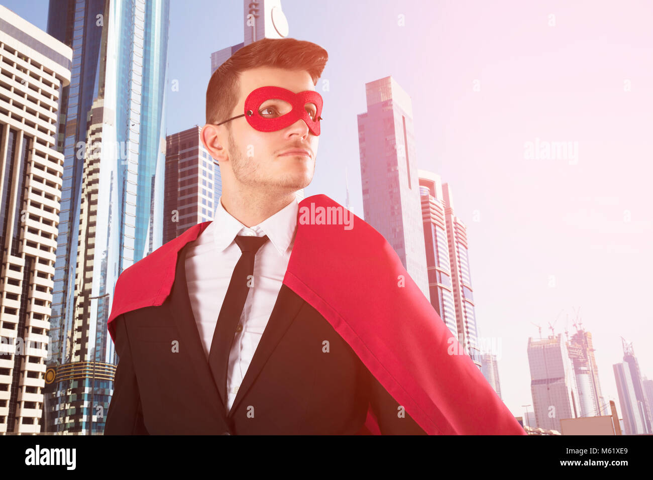 Junge Superheld Geschäftsmann auf der umgebenden Mauer mit Stadt Gebäude im Hintergrund Wolkenkratzer Stockfoto