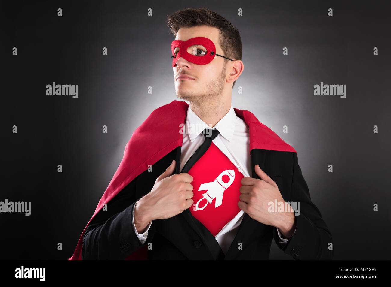 Junge Unternehmer in Kap Öffnung Shirt für Rakete Zeichen auf schwarzem Hintergrund Stockfoto