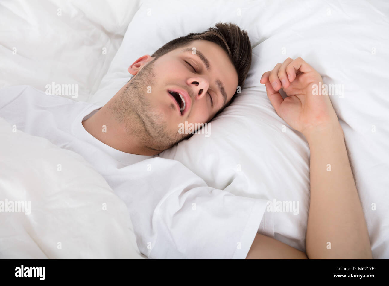 Blick auf Müde junge Mann Schnarchen während Tief schlafen im Bett Stockfoto