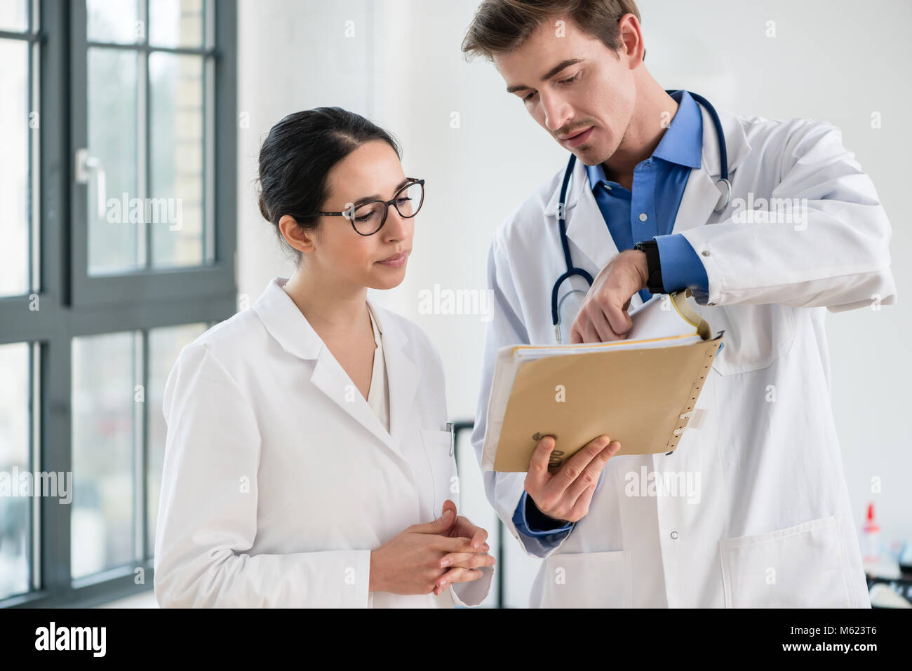 Zwei Ärzte zusammen Kontrolle der Krankenakte eines Patienten Stockfoto