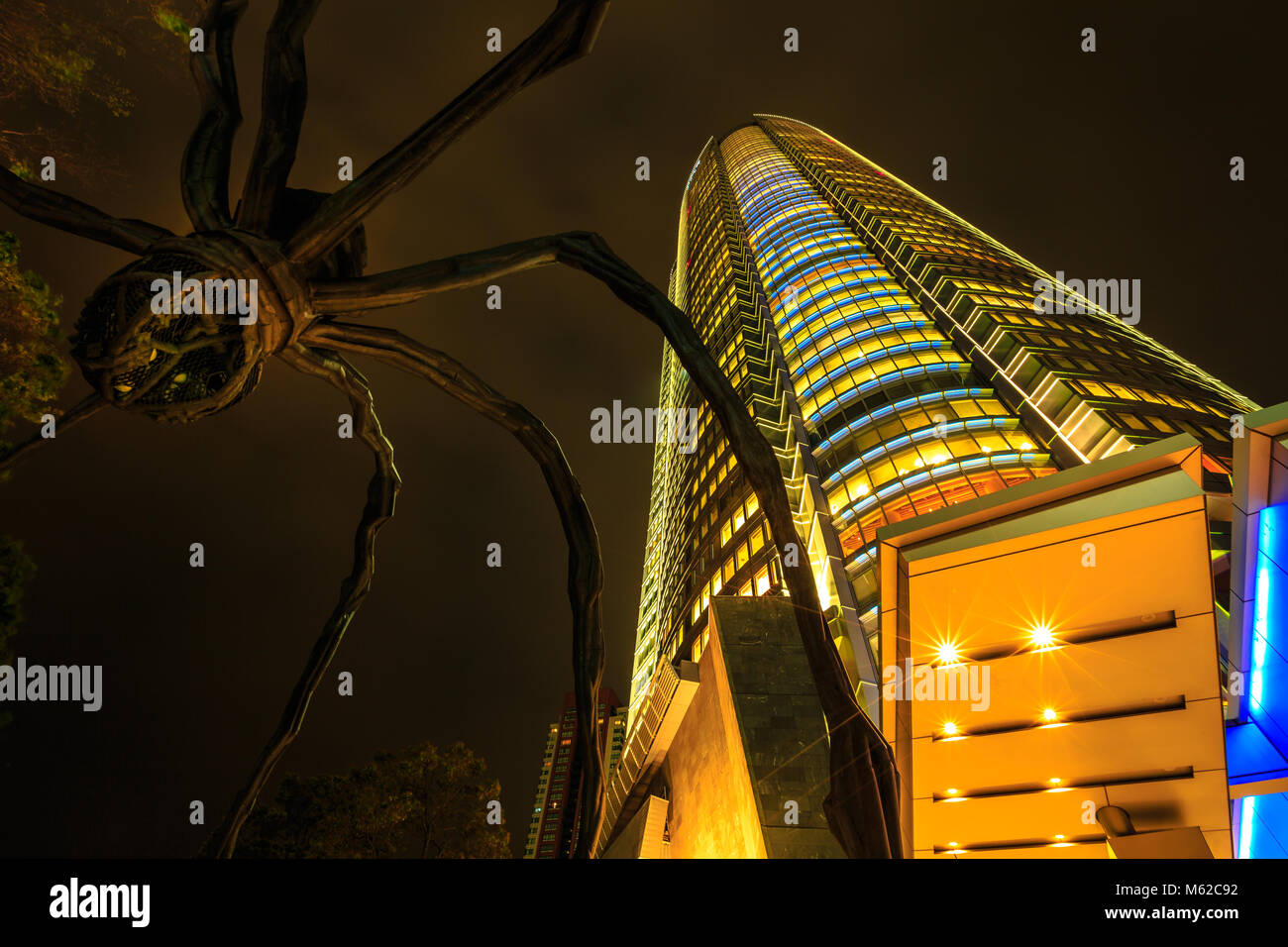 Tokyo, Japan - 20. April 2017: Low Angle View von Mori Tower und Maman Spider Bronze Skulptur in der Nacht in Roppongi Hills Komplex in Minato, Tokio beleuchtet. Nacht Szene. Stockfoto