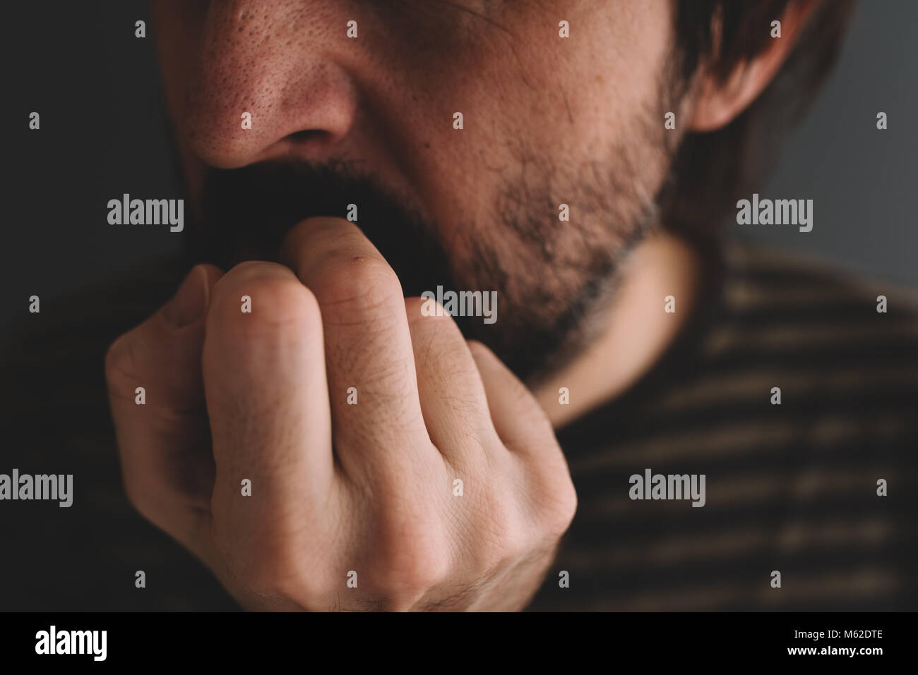 Nervöse Mann beißt Fingernägel, Low Key Close up mit selektiven Fokus Stockfoto