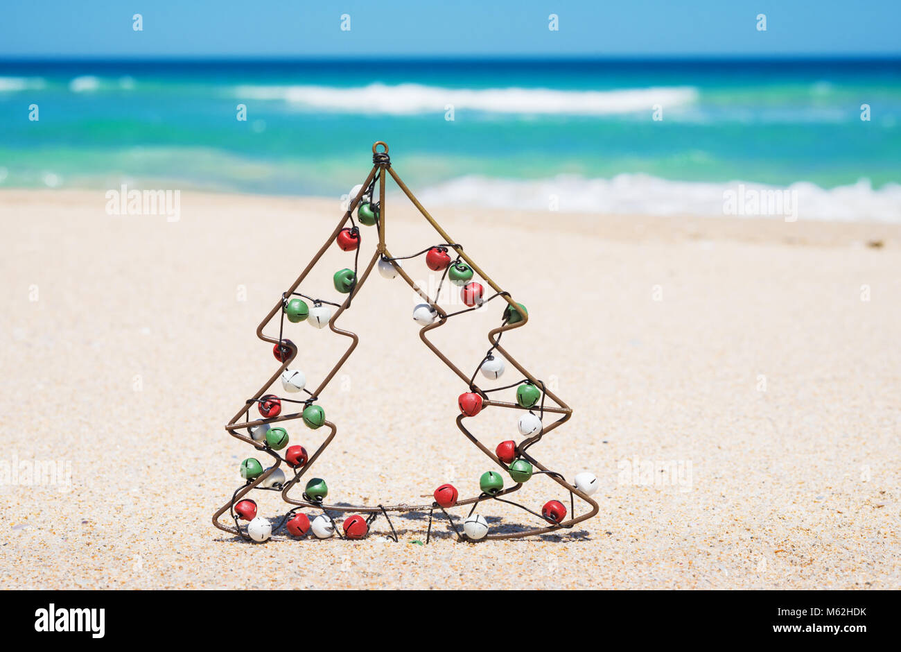 Kleine metall Weihnachtsbaum mit Jingle bells am Strand. Neues Jahr und Weihnachten Konzept Stockfoto