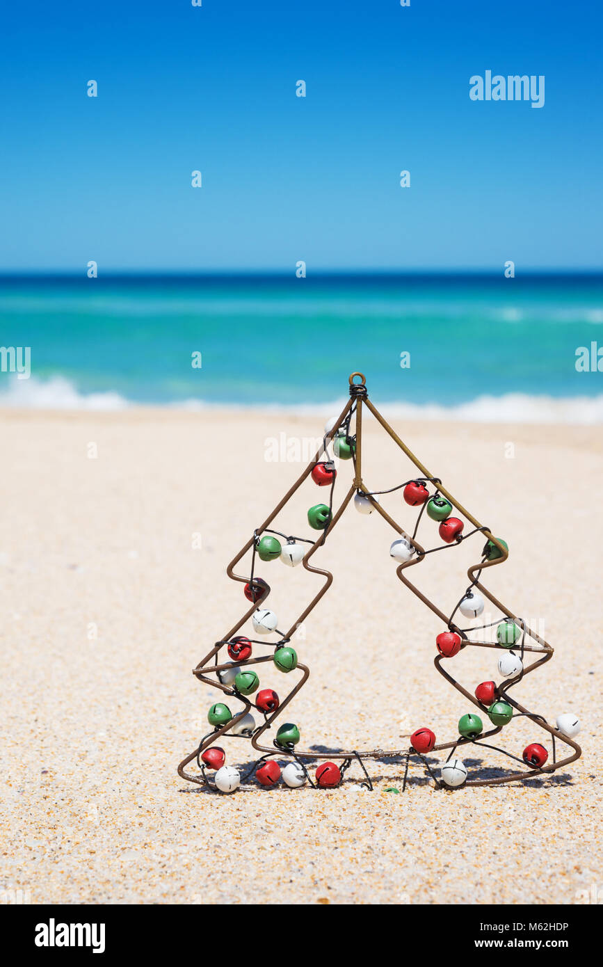 Kleine metall Weihnachtsbaum mit Jingle bells am Strand. Neues Jahr und Weihnachten Konzept Stockfoto