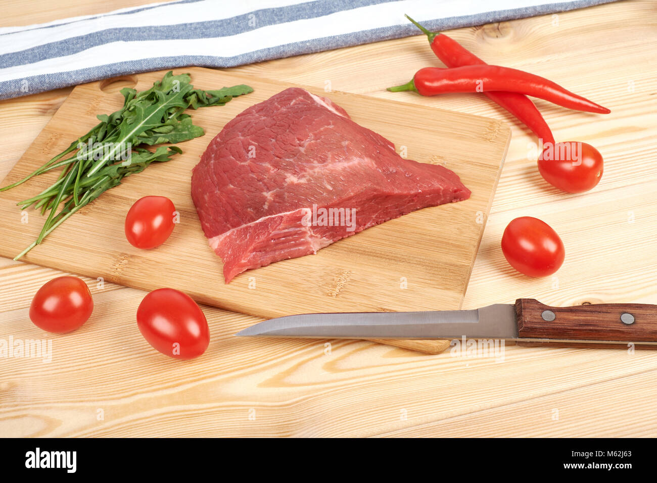 Rohes Rindfleisch Fleisch auf Schneidebrett mit Gemüse auf einem hölzernen Hintergrund Stockfoto