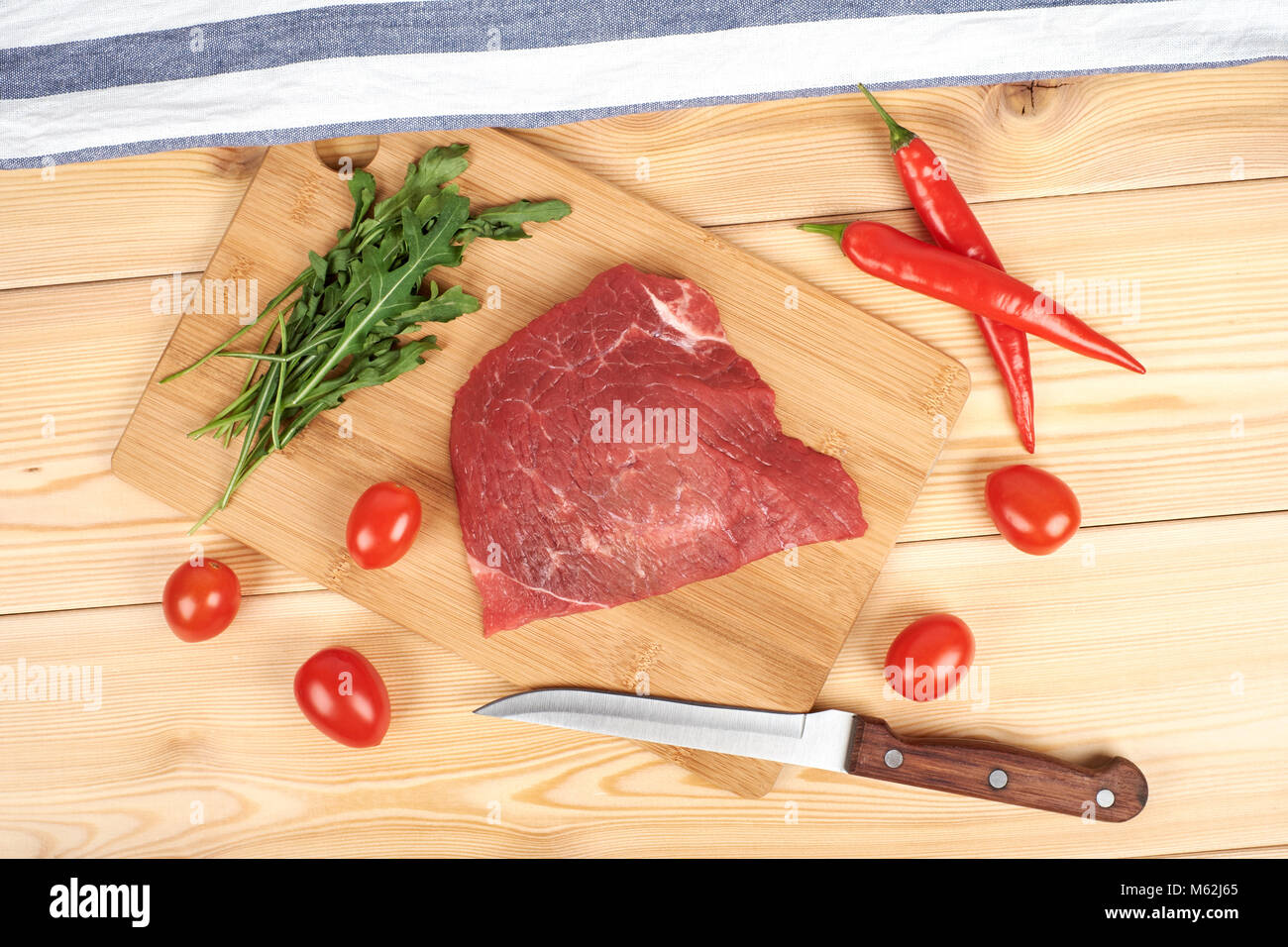 Rohes Rindfleisch Fleisch auf Schneidebrett mit Gemüse auf einem hölzernen Hintergrund Stockfoto