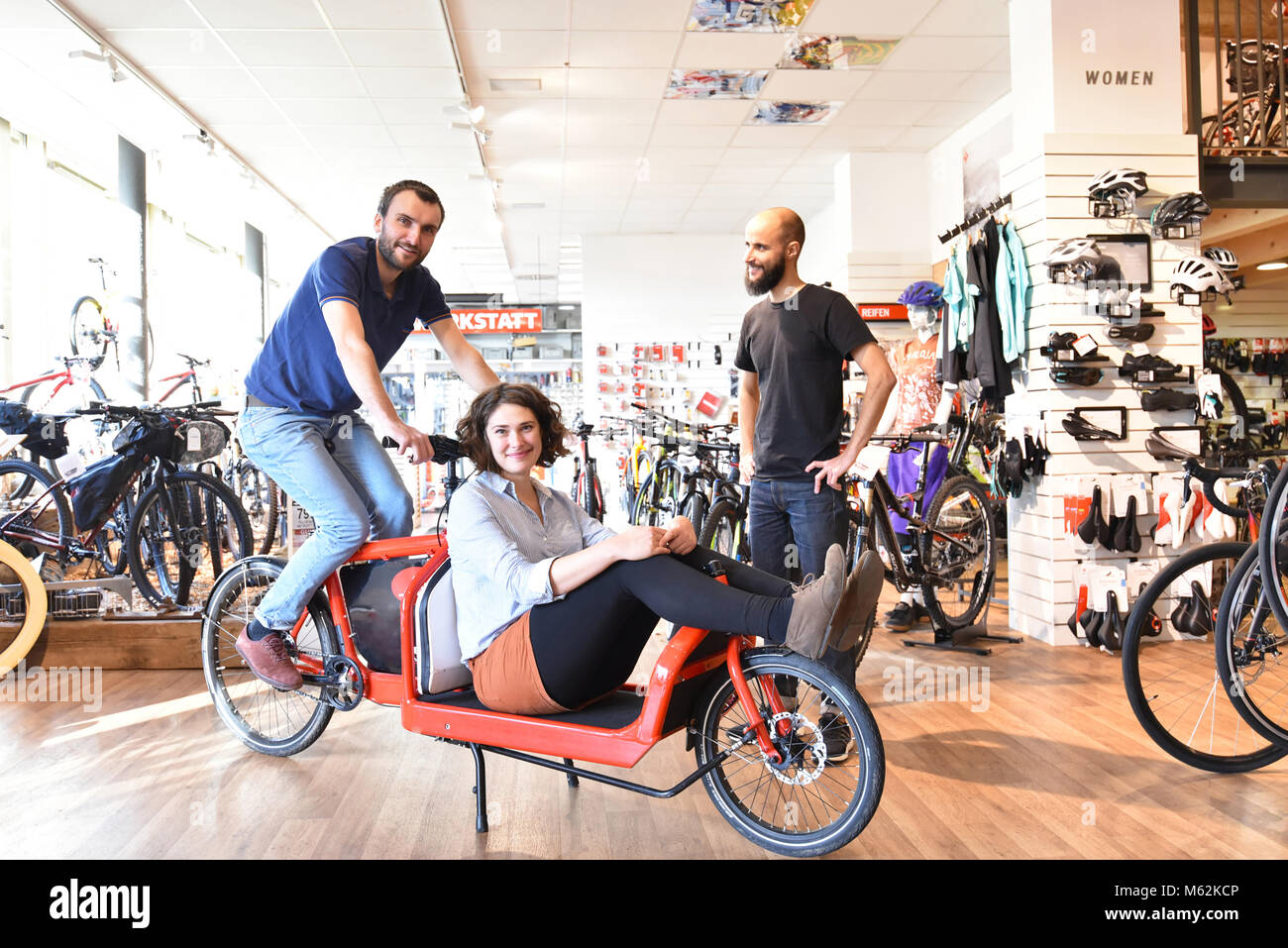 Kunden und Händler im Fahrrad Shop - Kauf und Reparatur von Fahrrädern - Paar getestet ein Transport fahrrad Stockfoto