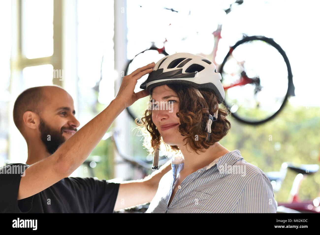 Fahrrad shop Beratung - Kunde testet ein fahrradhelm für die Straßenverkehrssicherheit Stockfoto