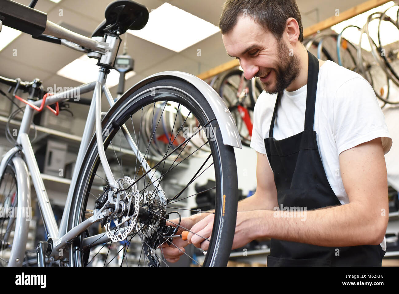 Freundlich und kompetent Fahrradmechaniker in einer Werkstatt Reparaturen ein Fahrrad Stockfoto
