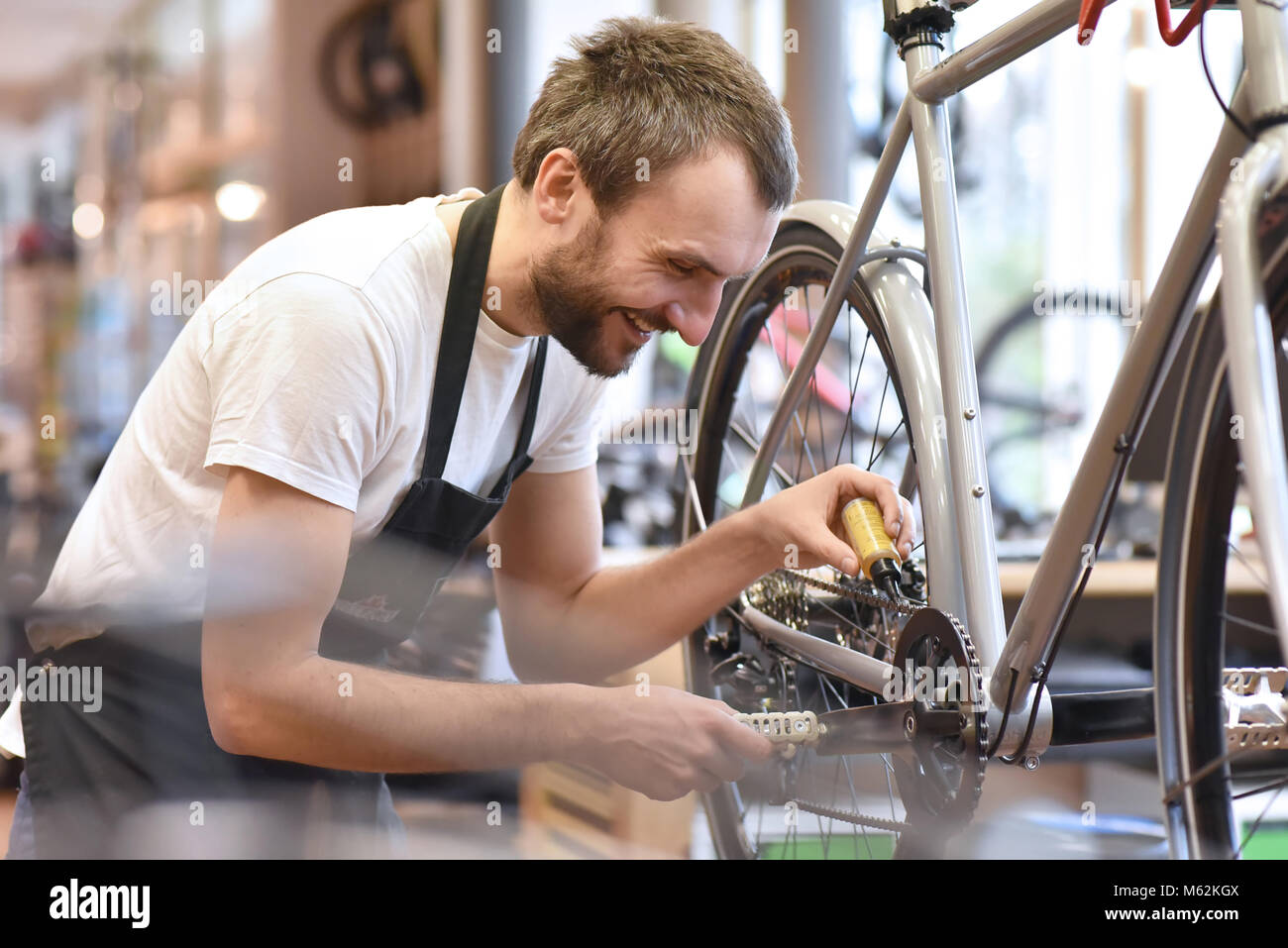 Mechaniker in einer Fahrradreparaturwerkstatt Ölen der Kette der ein Fahrrad Stockfoto