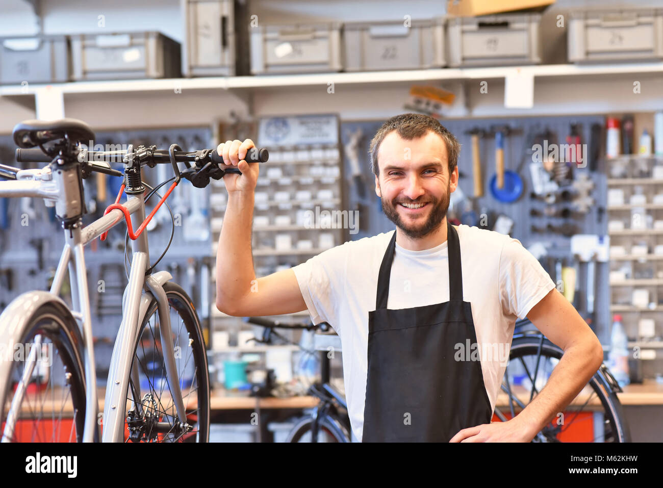 Porträt eines freundlichen und kompetenten Fahrradmechaniker in einer Werkstatt Reparaturen ein Fahrrad Stockfoto