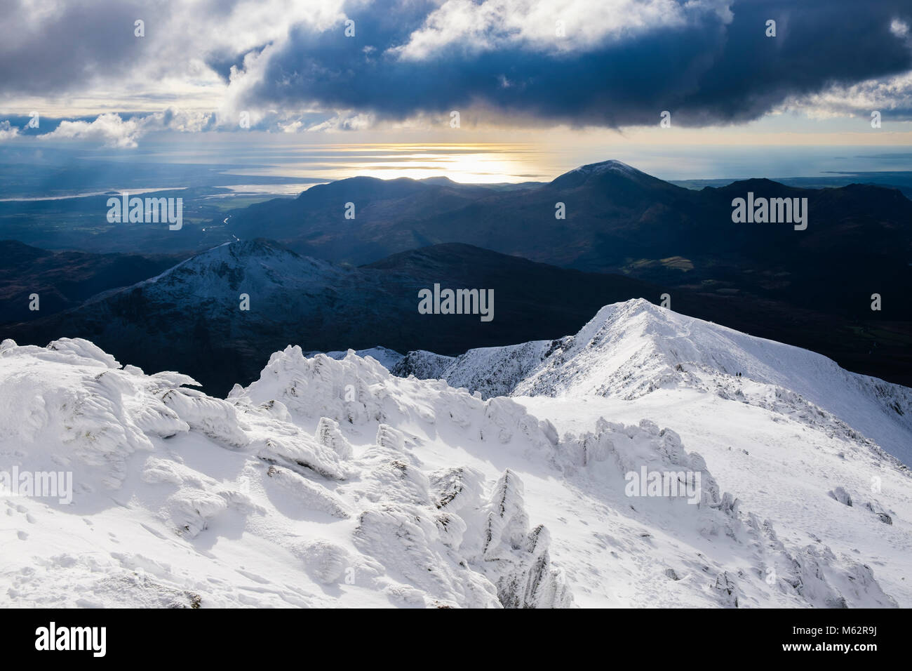 Dramatischer Blick auf die Küste von Snowdon south Ridge auf Menai Bridge Main mit Schnee im Winter in Snowdonia National Park (Eryri). Gwynedd, Wales, Großbritannien, Großbritannien Stockfoto