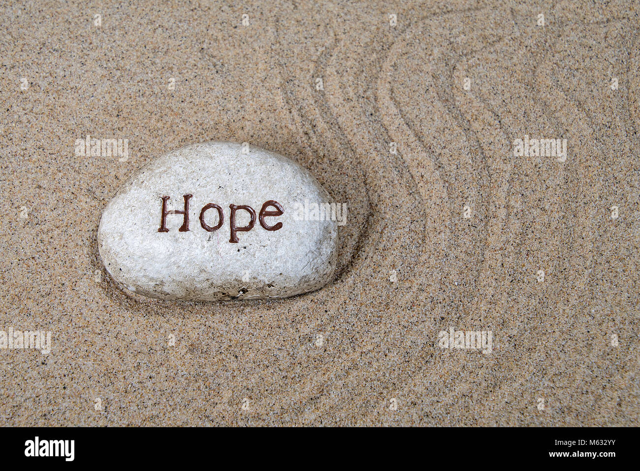 Hoffe Text eingraviert auf einem Felsen am Strand Sand mit Swirl design Stockfoto