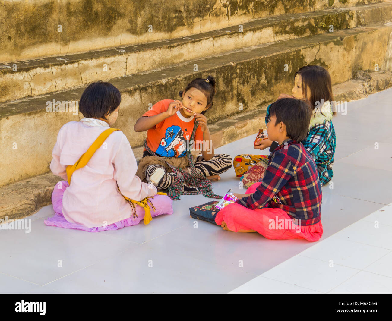 BAGAN, MYANMAR - Januar 6, 2018 Burmesische Kinder außerhalb der Manuha Tempel sitzen. Stockfoto