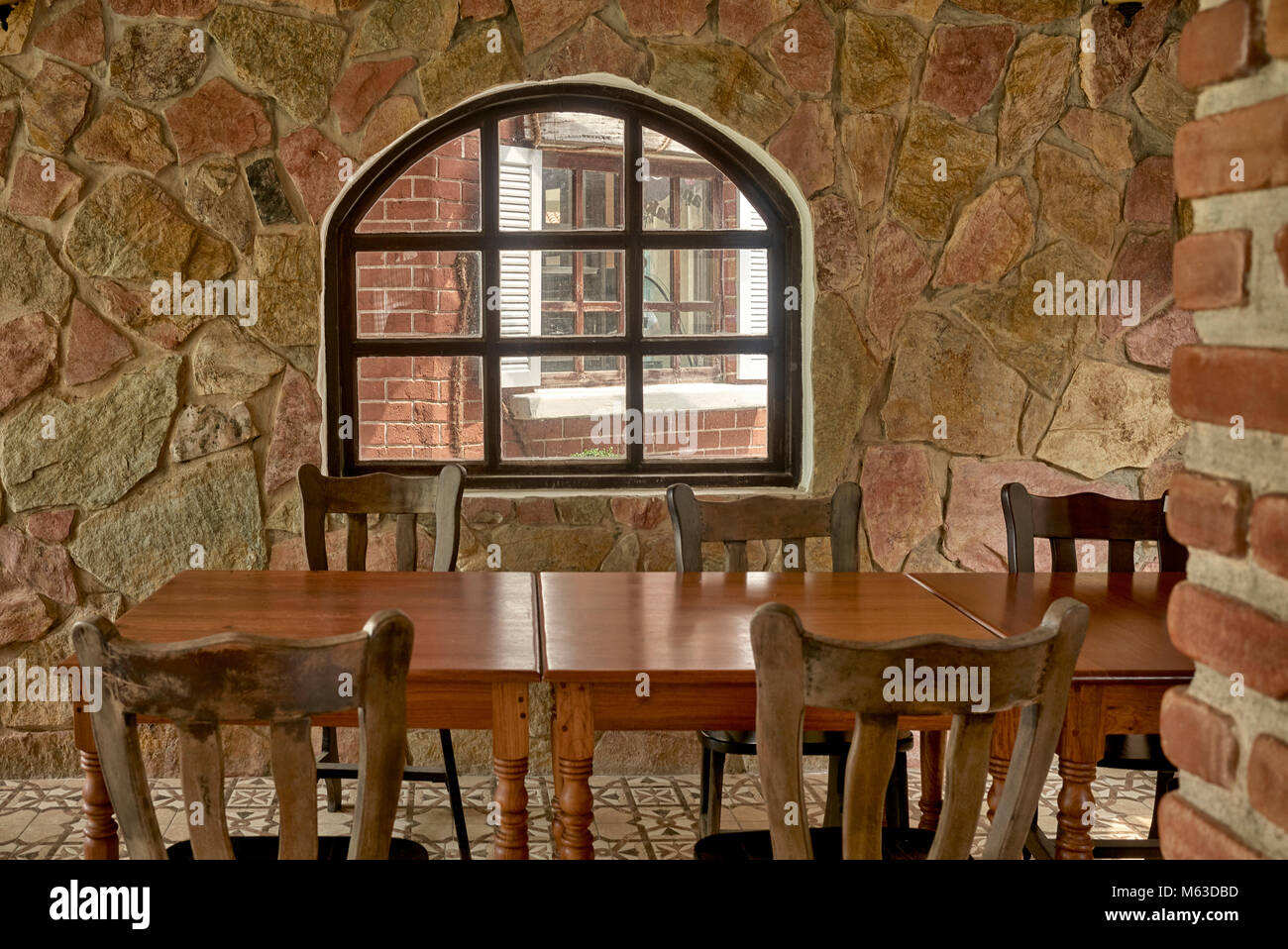 Rustikale Steineinrichtung im Restaurant mit Holztischen und -Stühlen. Vintage Restaurant Interieur mit gemütlichen Ecke Dining. Stockfoto