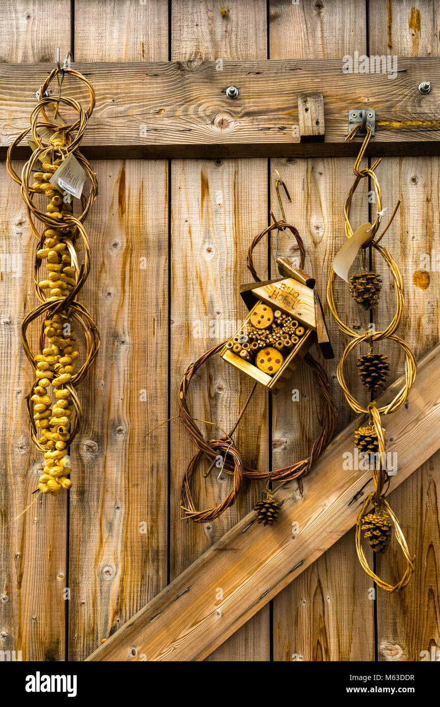 Ein bug Hotel und andere natürliche Produkte hängen von einem Holz Scheunentor. Stockfoto