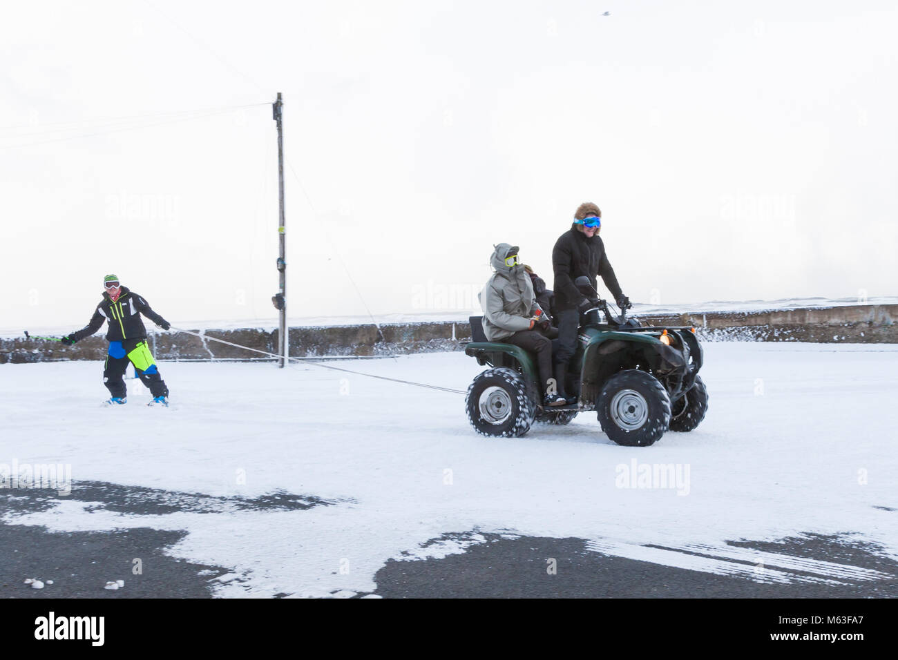 Männer Spaß mit ein Quad ziehen ein Snowboard durch Nevsehir Village UK Stockfoto