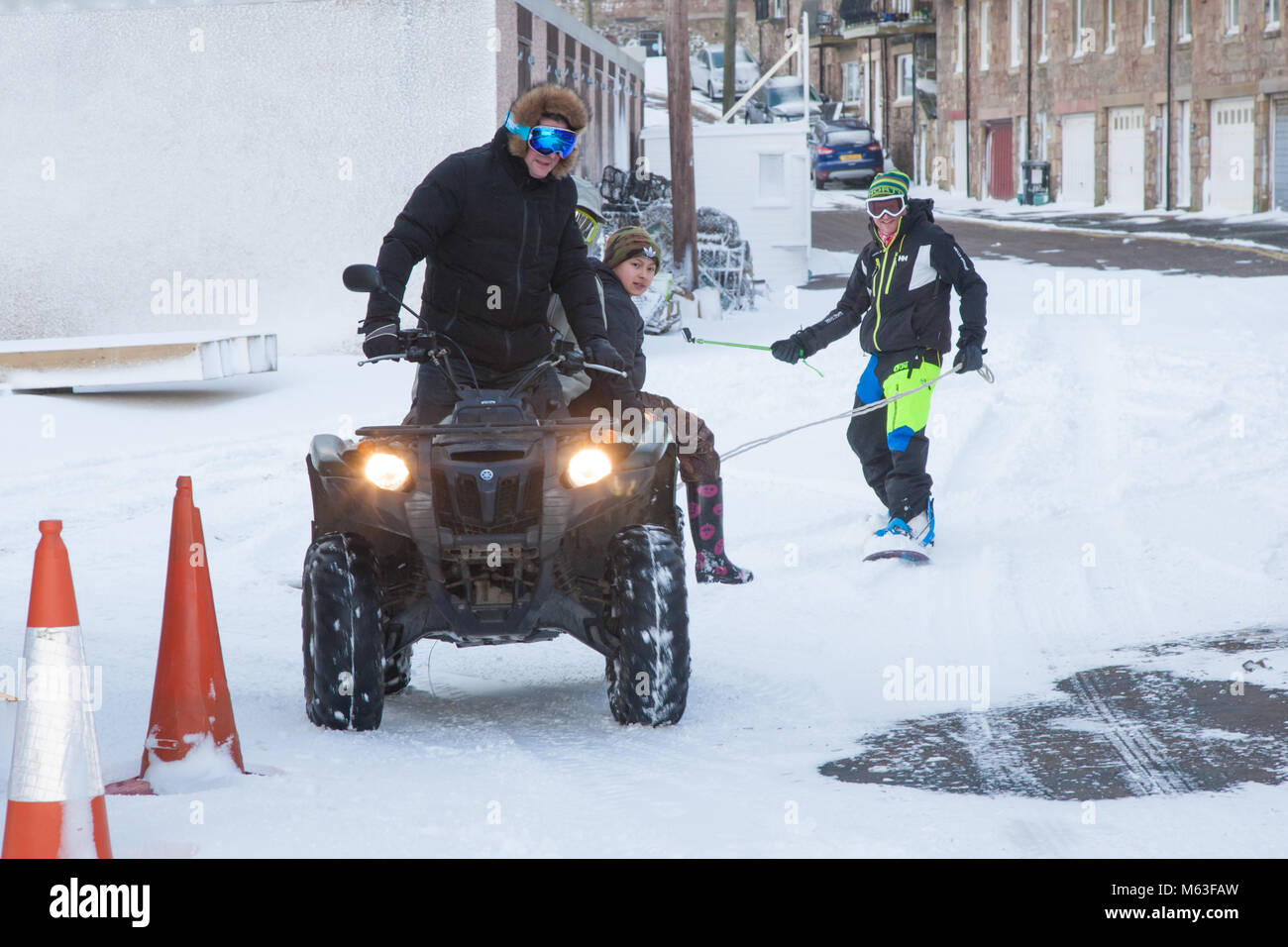 Männer Spaß mit ein Quad ziehen ein Snowboard durch Nevsehir Village UK Stockfoto