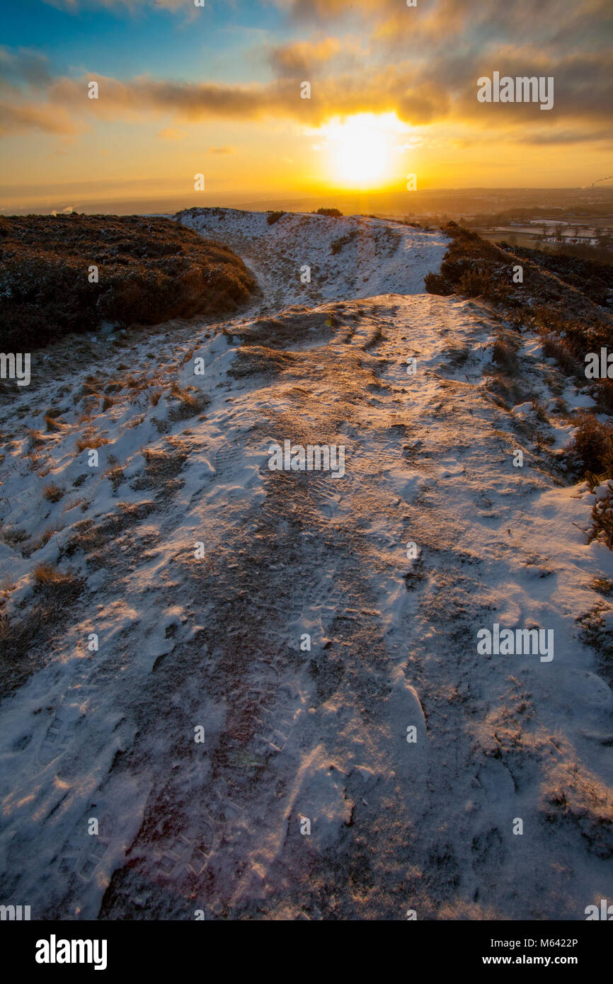 Flintshire, Wales, UK UK Wetter: Das Tier aus dem Osten weiterhin Chaos in vielen Bereichen in Großbritannien mit Schnee und Frost, Sturm Emma Ankunft morgen anrichten. Eine schöne gefrorene Landschaft bei Sonnenaufgang auf einem Pfad, der Konturen der Eisenzeit Hill Fort der Moel y Gaer auf halkyn Berg. Stockfoto