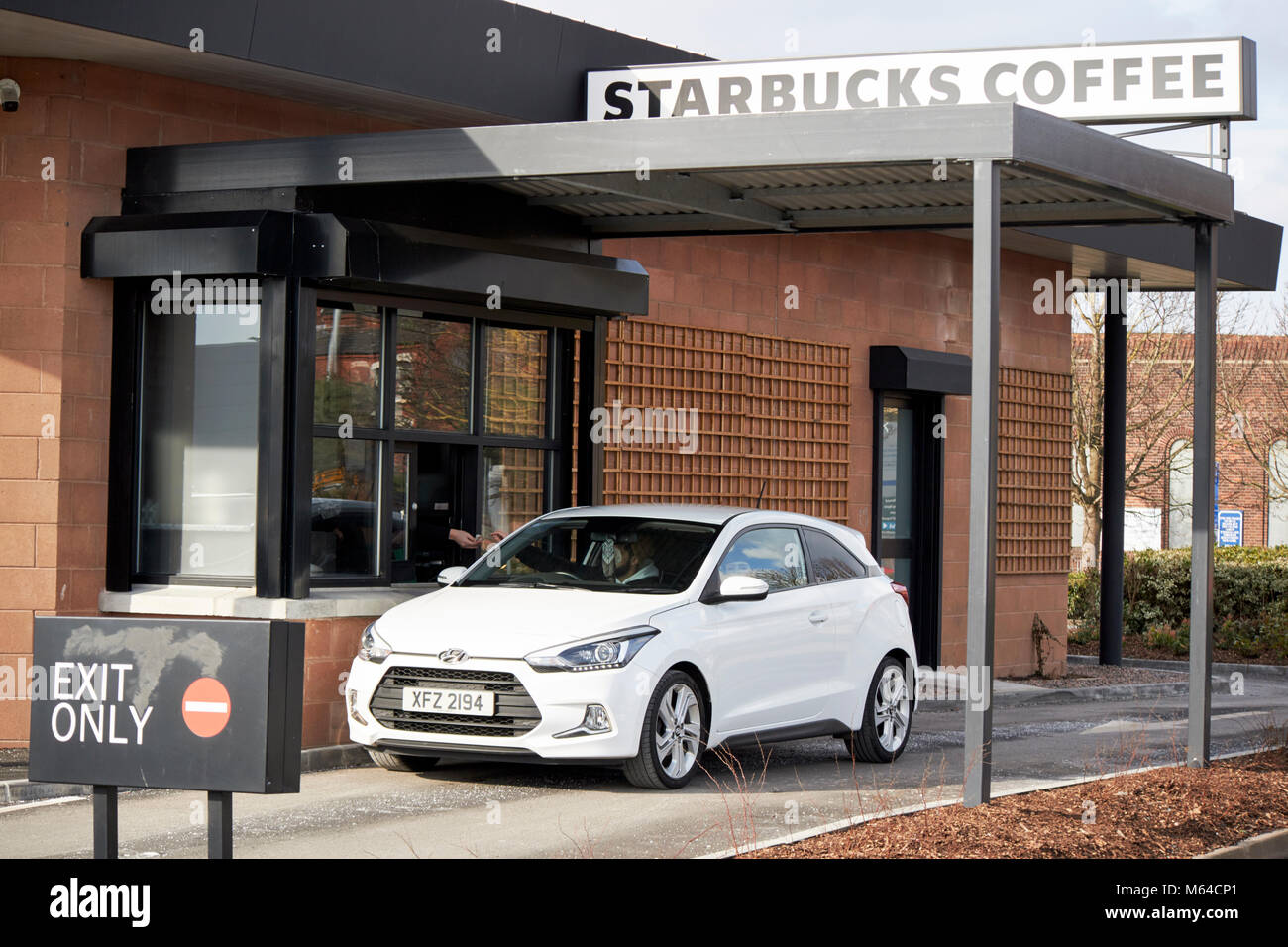 Bestellung von Kaffee aus dem Auto bei Starbucks Drive Thru in Großbritannien Stockfoto