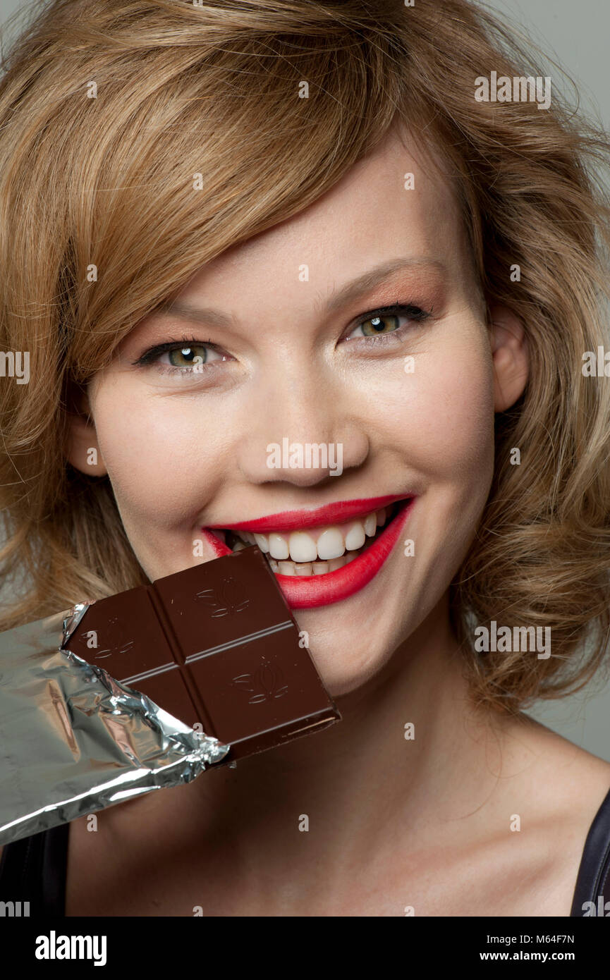 Glückliche Frau in bar von dunkler Schokolade beißen Stockfoto