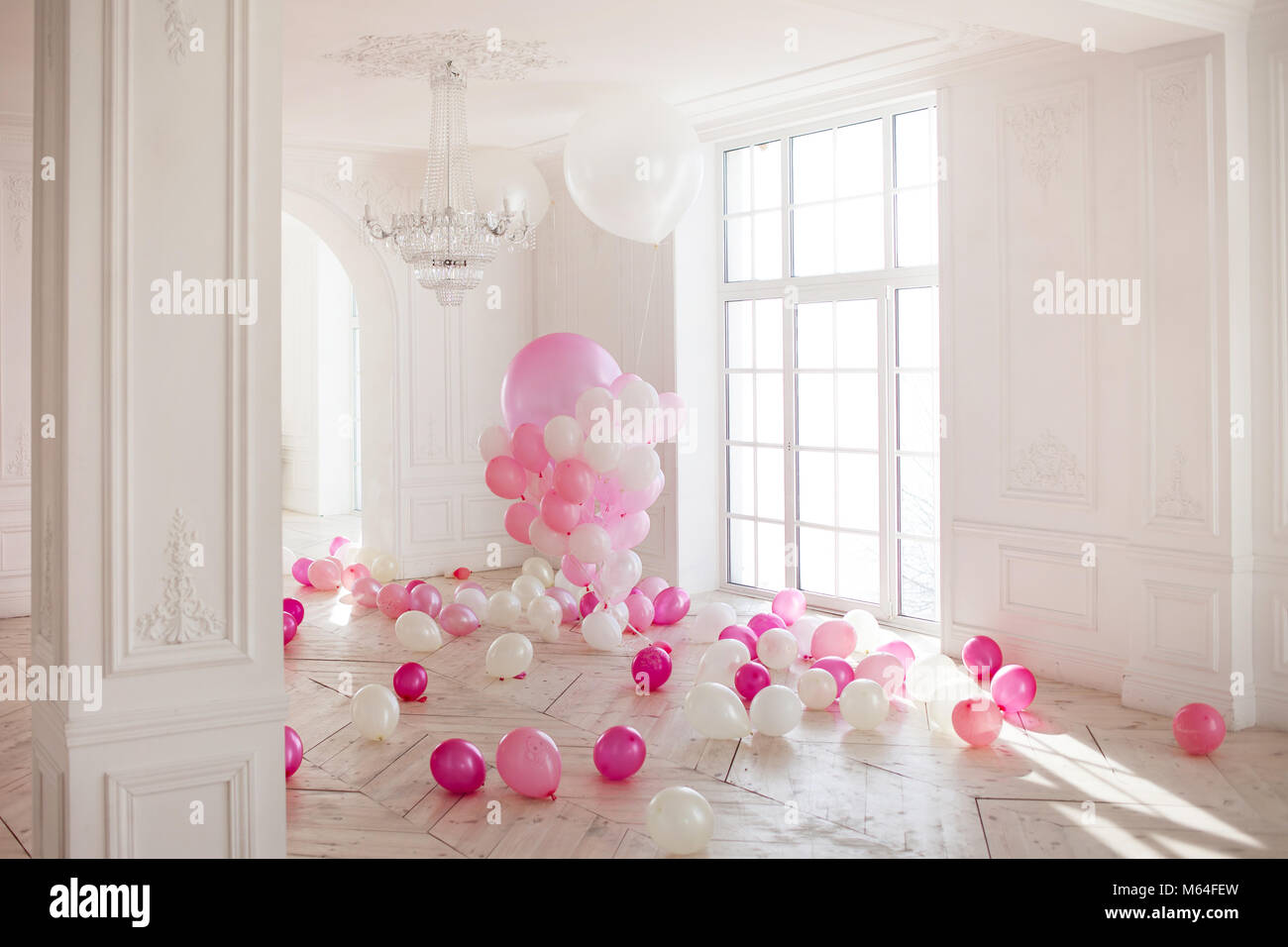 Luxuriöses Wohnzimmer mit großem Fenster auf den Boden. Der Palast ist mit rosa Luftballons gefüllt. Stockfoto