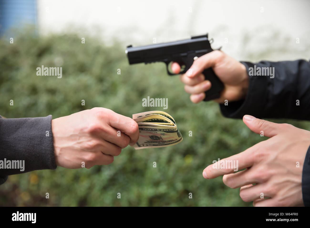 Nahaufnahme der Räuber Hand mit Pistole Bedroht jemand Geld geben Stockfoto