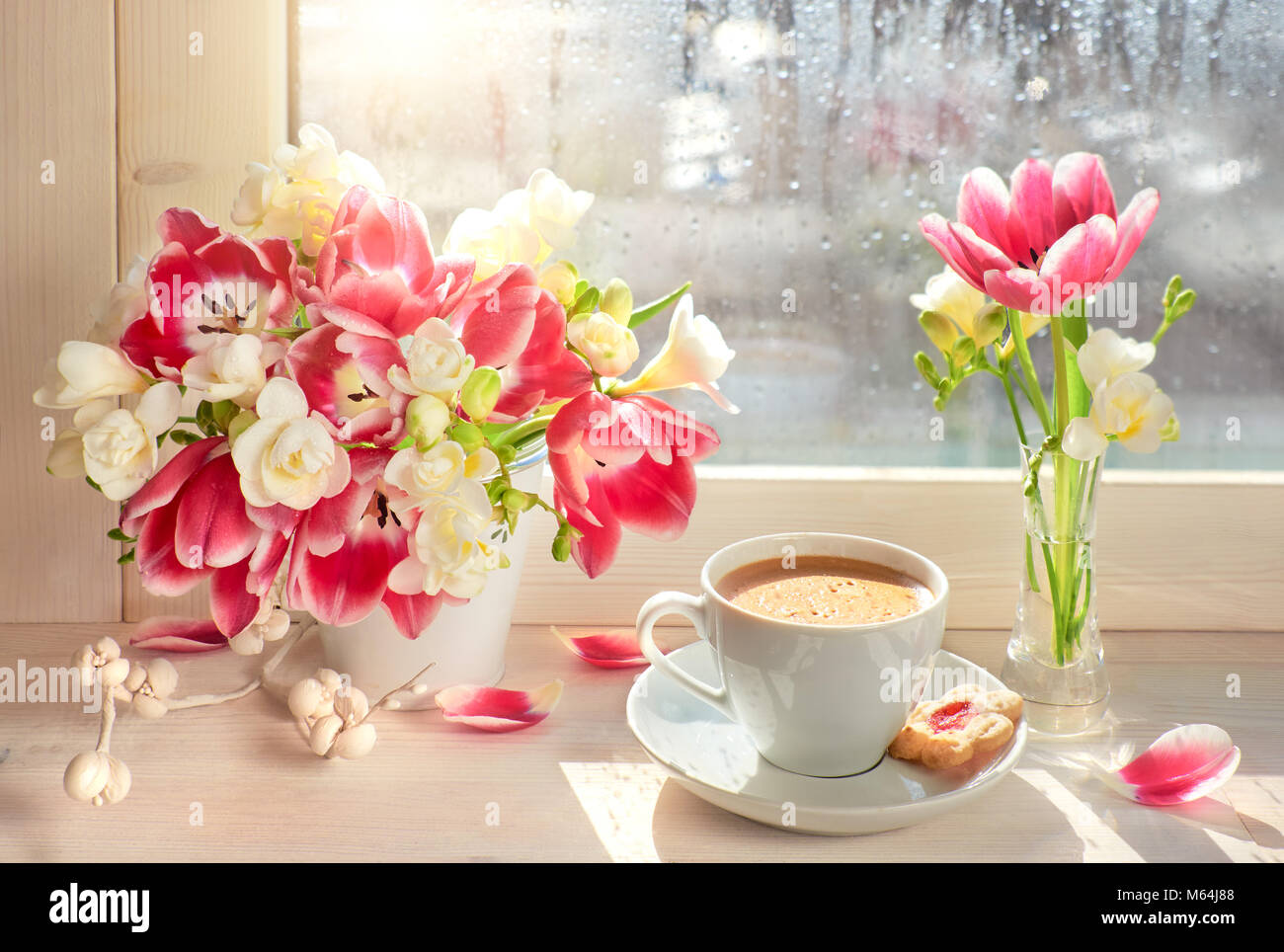 Tasse Kaffee am Fenster, Sonne nach dem Regen. Frühling Blumen: rosa Tulpen  und weißen Freesien Stockfotografie - Alamy