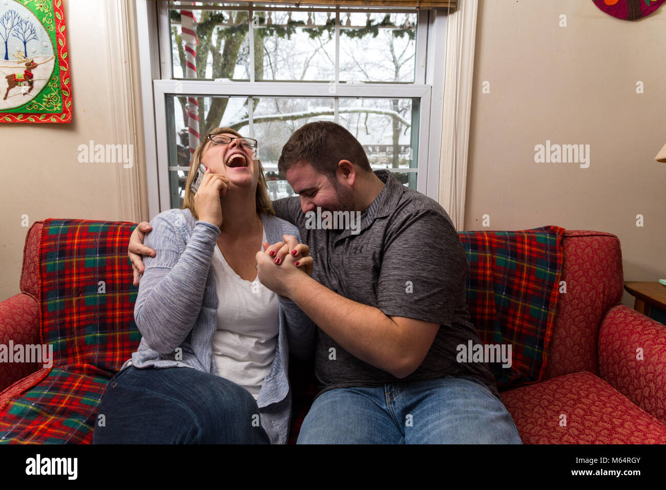 Eine Junge kaukasier Paar wartet aufgeregt und betet für eine gute Nachricht, da Sie sitzen auf Ihren Wohnzimmer Couch. Stockfoto