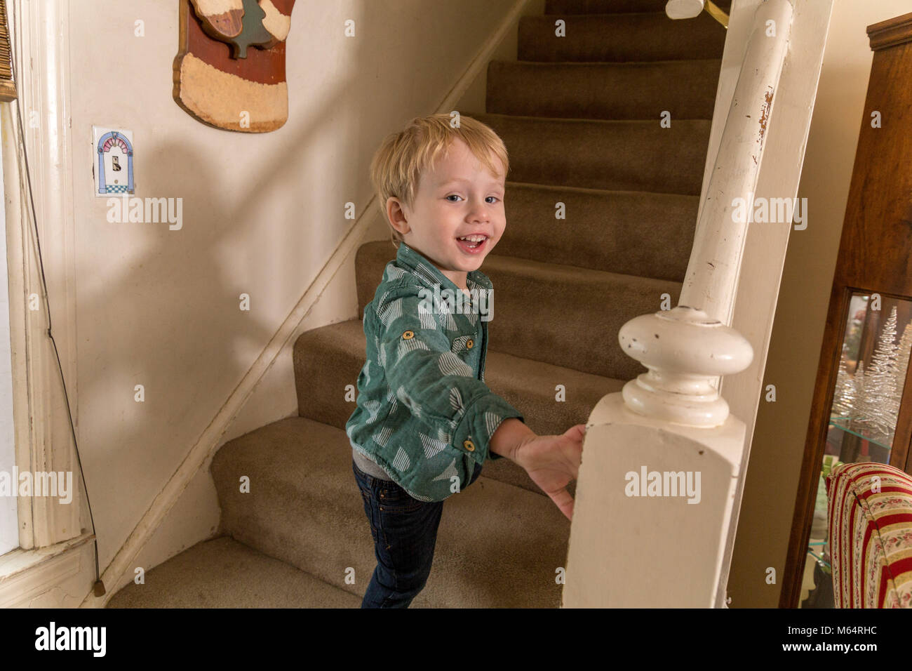Eine Junge kaukasier Toddler Boy spielt auf einem Teppichboden Treppe in seinem Vorstadthaus Stockfoto