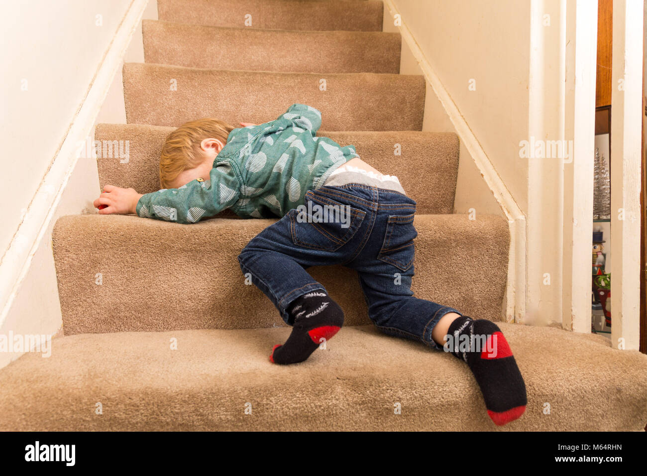 Eine Junge kaukasier Toddler Boy spielt auf einem Teppichboden Treppe in seinem Vorstadthaus Stockfoto