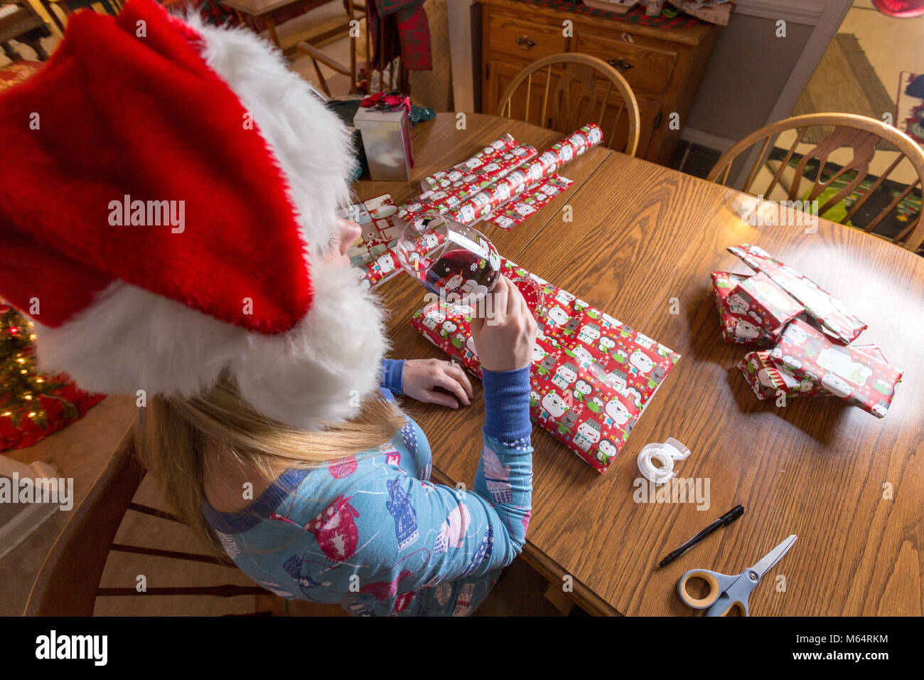 Junge kaukasier Frau Wraps Weihnachtsgeschenke und Wein trinken und Tragen Schlafanzug in Ihr Wohnzimmer Stockfoto