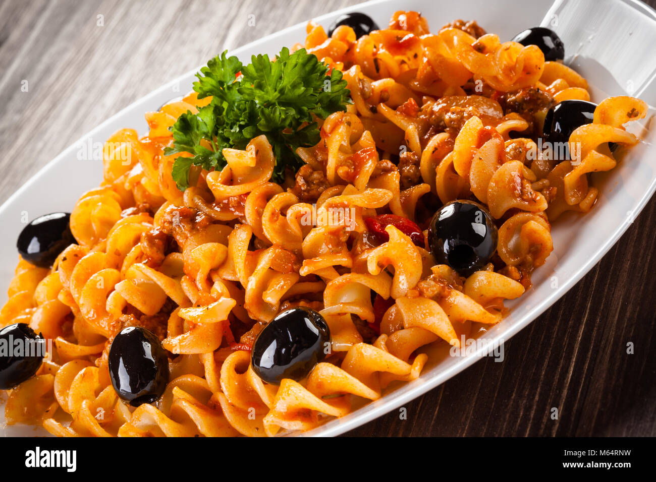 Pasta mit Fleisch und Tomatensoße und Gemüse auf hölzernen Tisch ...