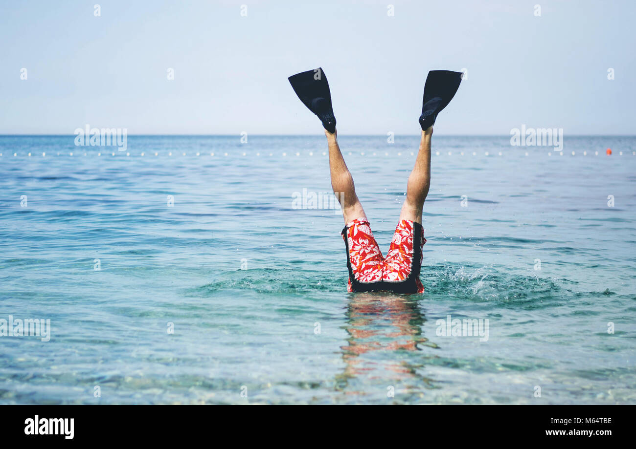 Spaß am Meer. Die männlichen Beine mit Flossen schwimmen über der Wasseroberfläche. Stockfoto